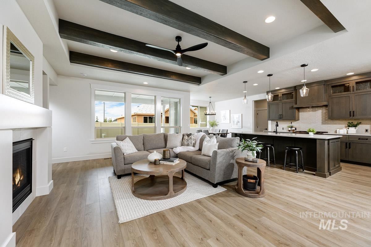 Living area with beamed ceiling, a ceiling fan, light wood finished floors, recessed lighting, and a glass covered fireplace