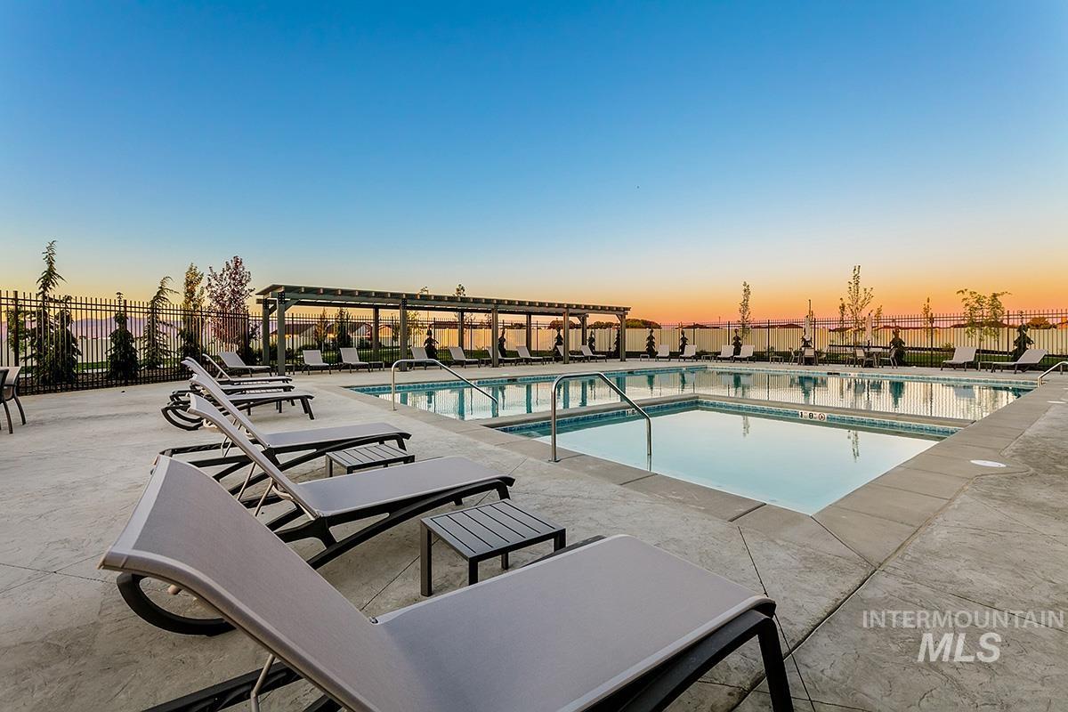 Pool at dusk featuring a community pool and a patio