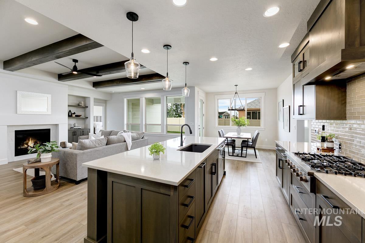 Kitchen with beamed ceiling, recessed lighting, pendant lighting, wall chimney exhaust hood, and stainless steel appliances
