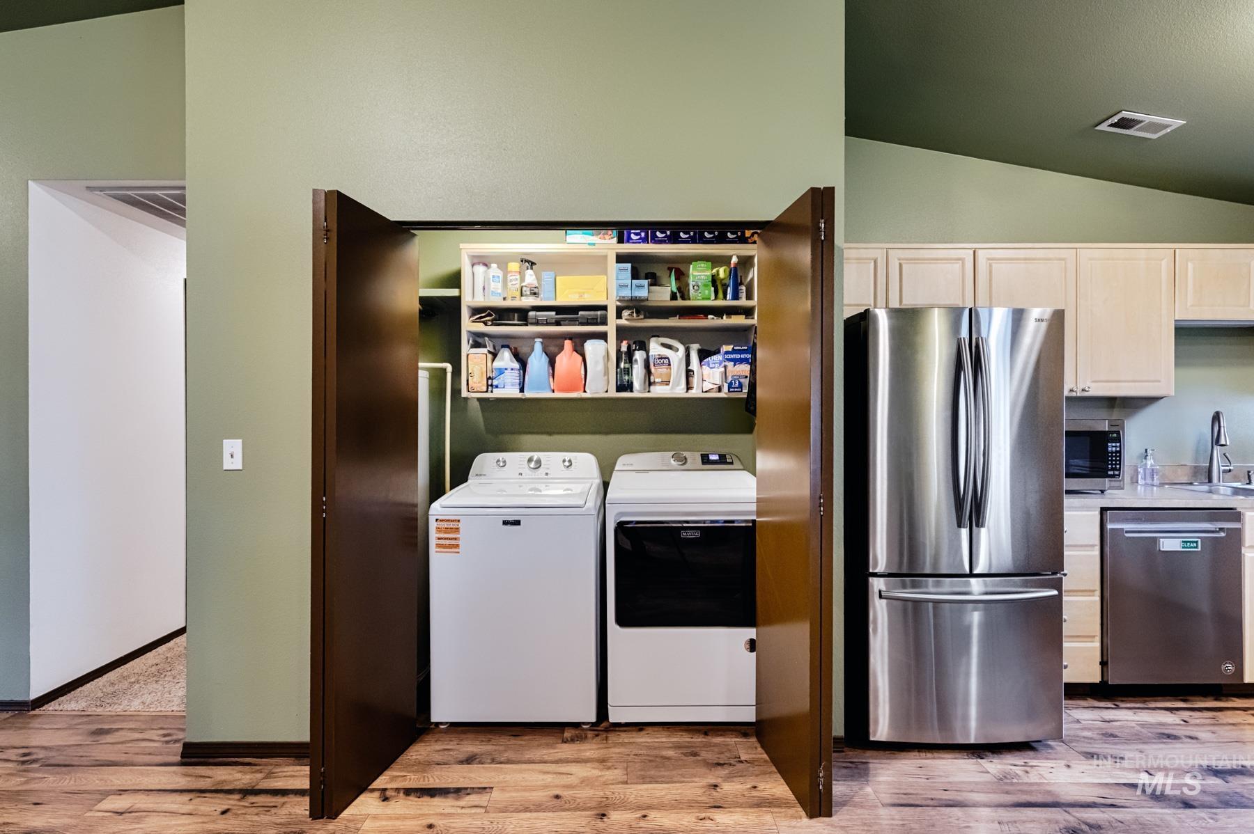 Laundry area with independent washer and dryer, light wood-style flooring, and lofted ceiling