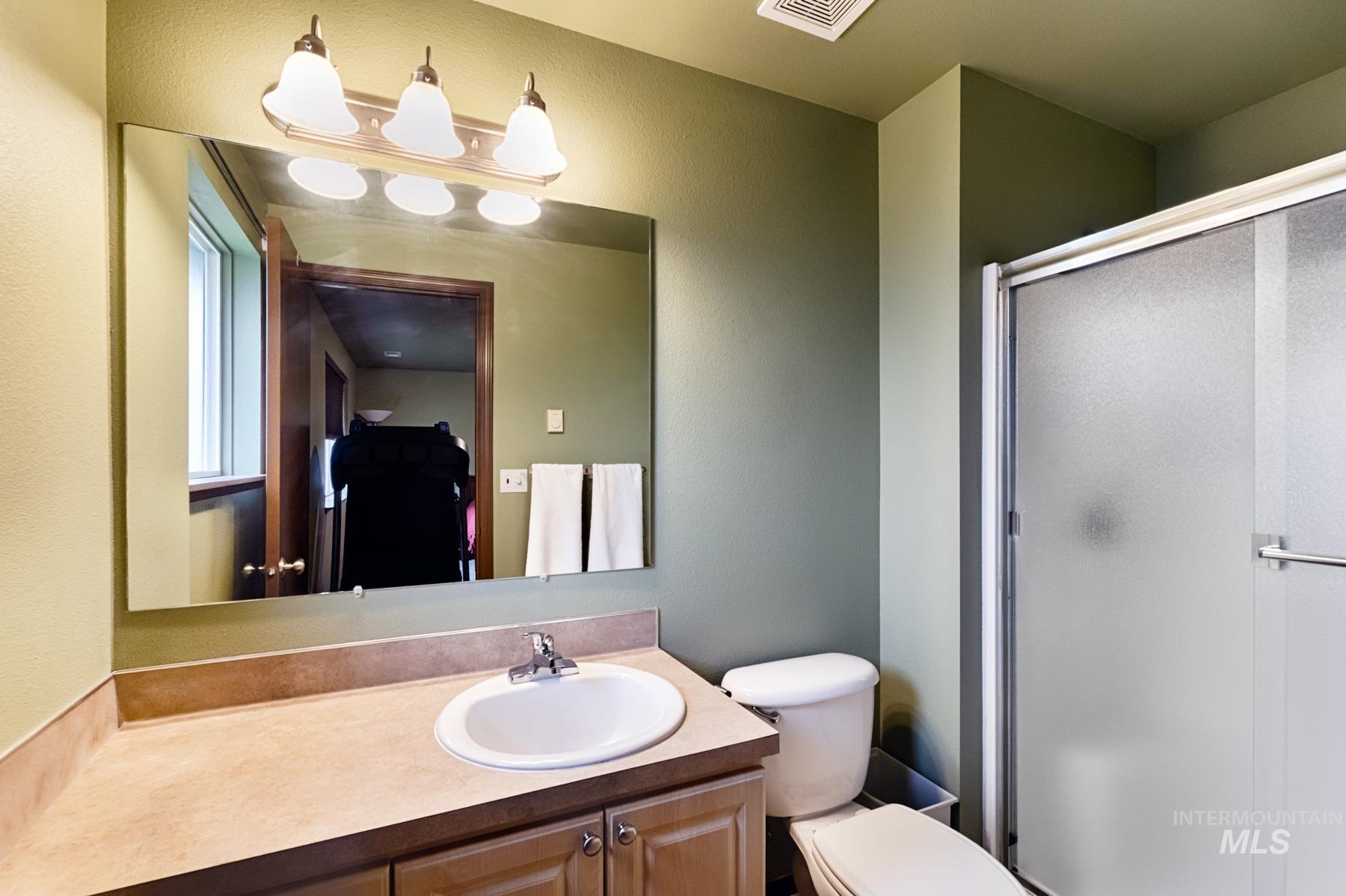 Full bathroom featuring a stall shower, vanity, and a textured wall
