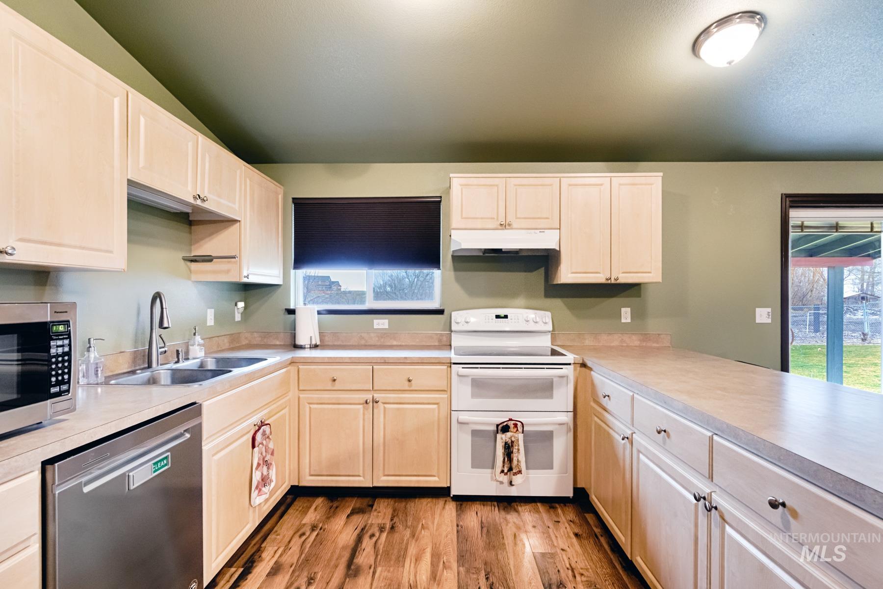 Kitchen with stainless steel appliances, light countertops, light wood-style floors, and light wood finish cabinetry
