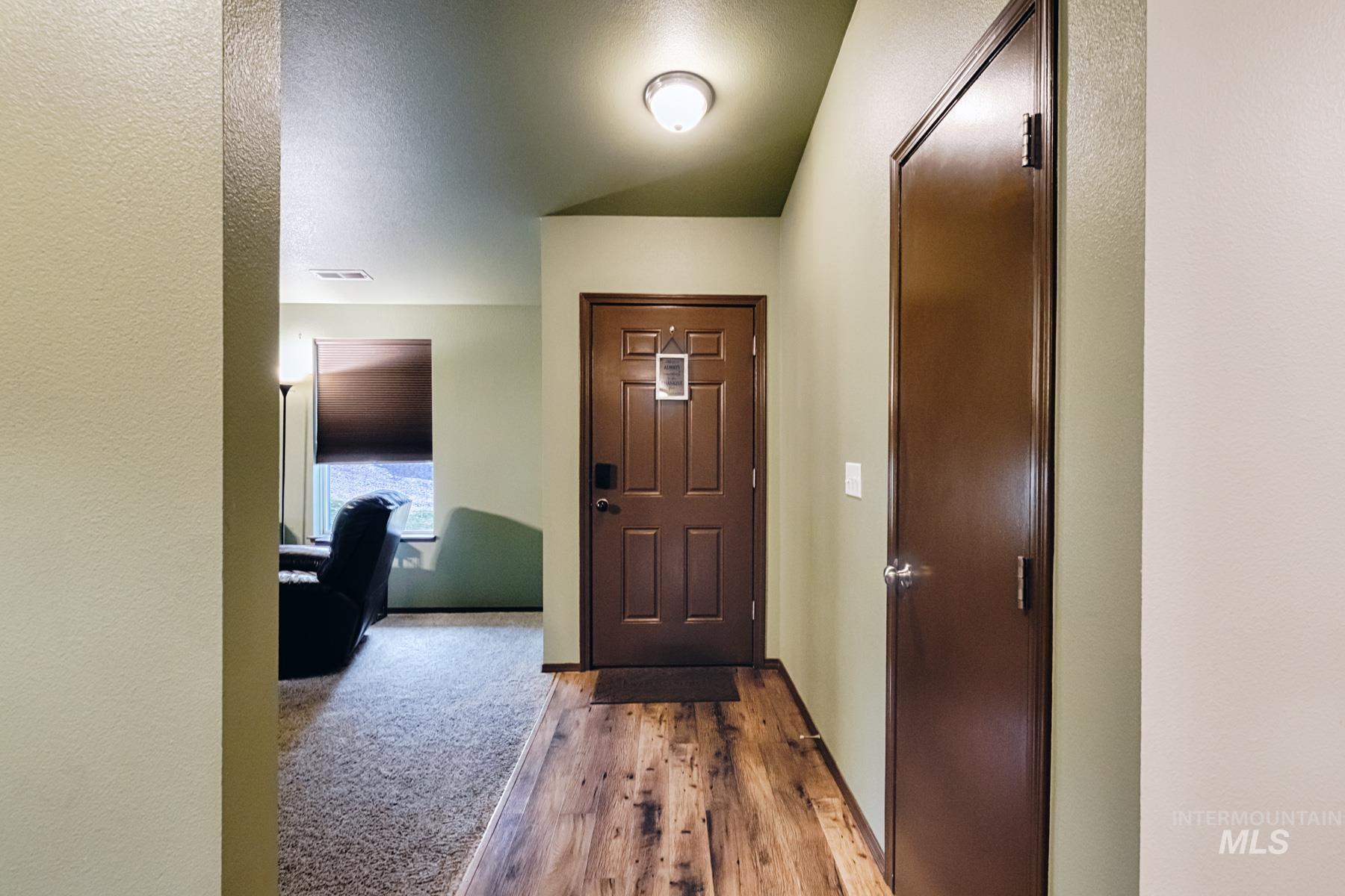 Entryway featuring wood finished floors, a textured wall, and a textured ceiling
