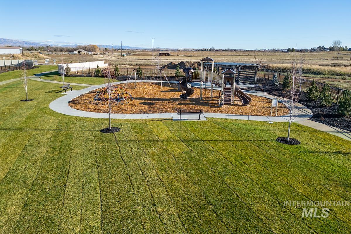 Community playground featuring a multi-level play structure with slides, swings, and a wood chip surface