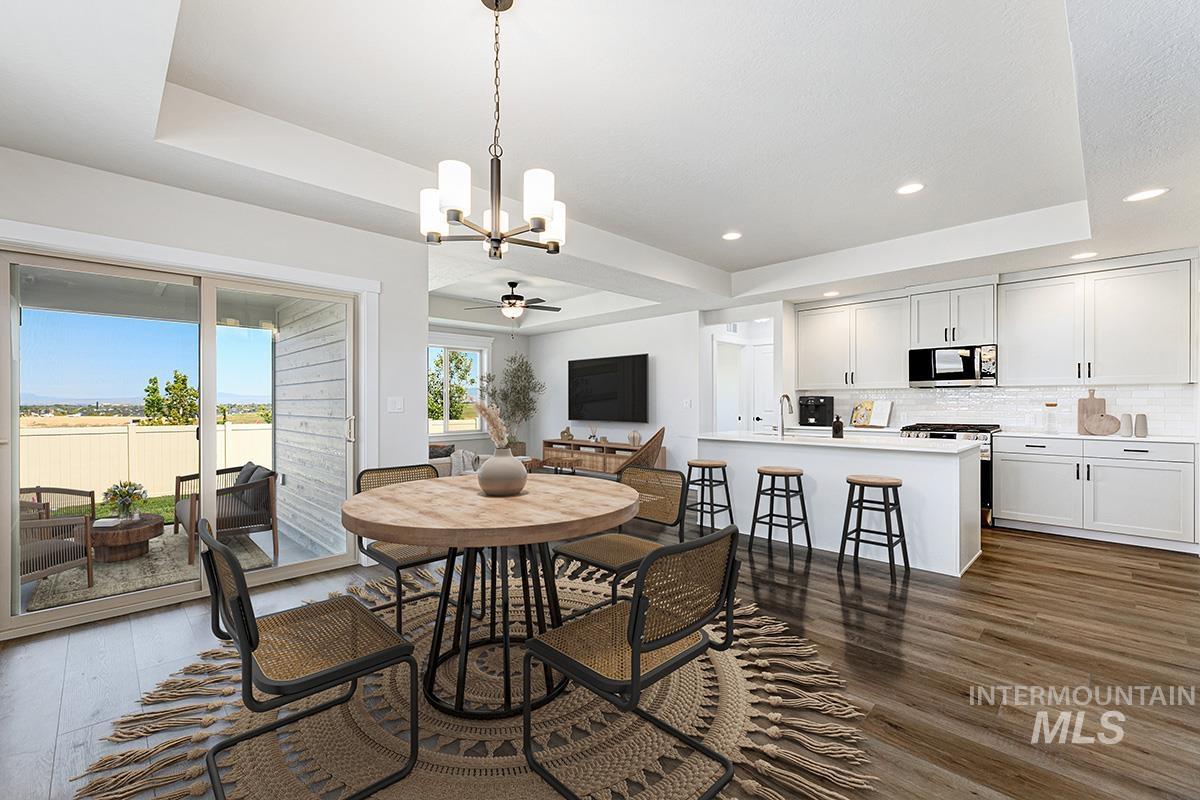 Open-concept living area featuring wood-finish flooring, a contemporary chandelier, and a sliding glass door to an outdoor patio