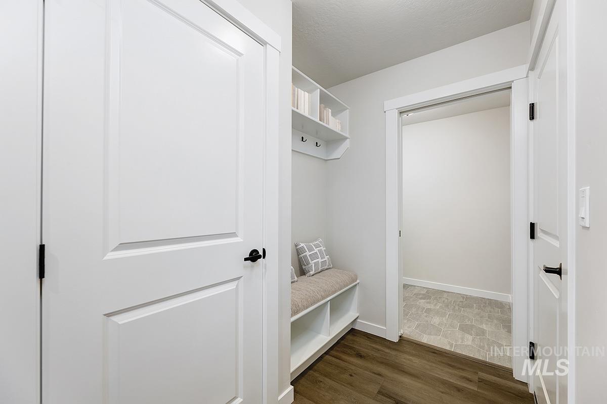 Entryway featuring wood-finish flooring, white paneled doors with matte black hardware, and an integrated bench with cubby storage