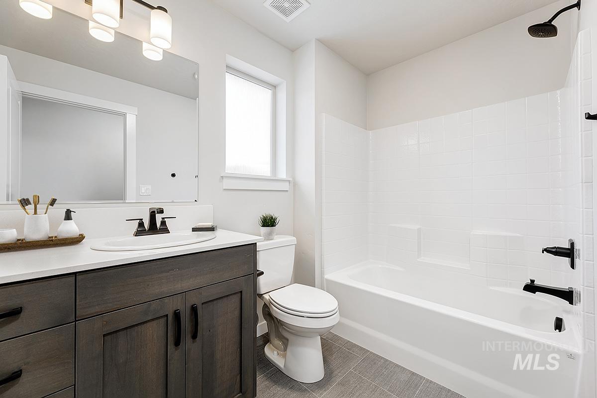 Bathroom featuring a dark wood-finish vanity with a white countertop and undermount sink, matte black faucet, and a large mirror