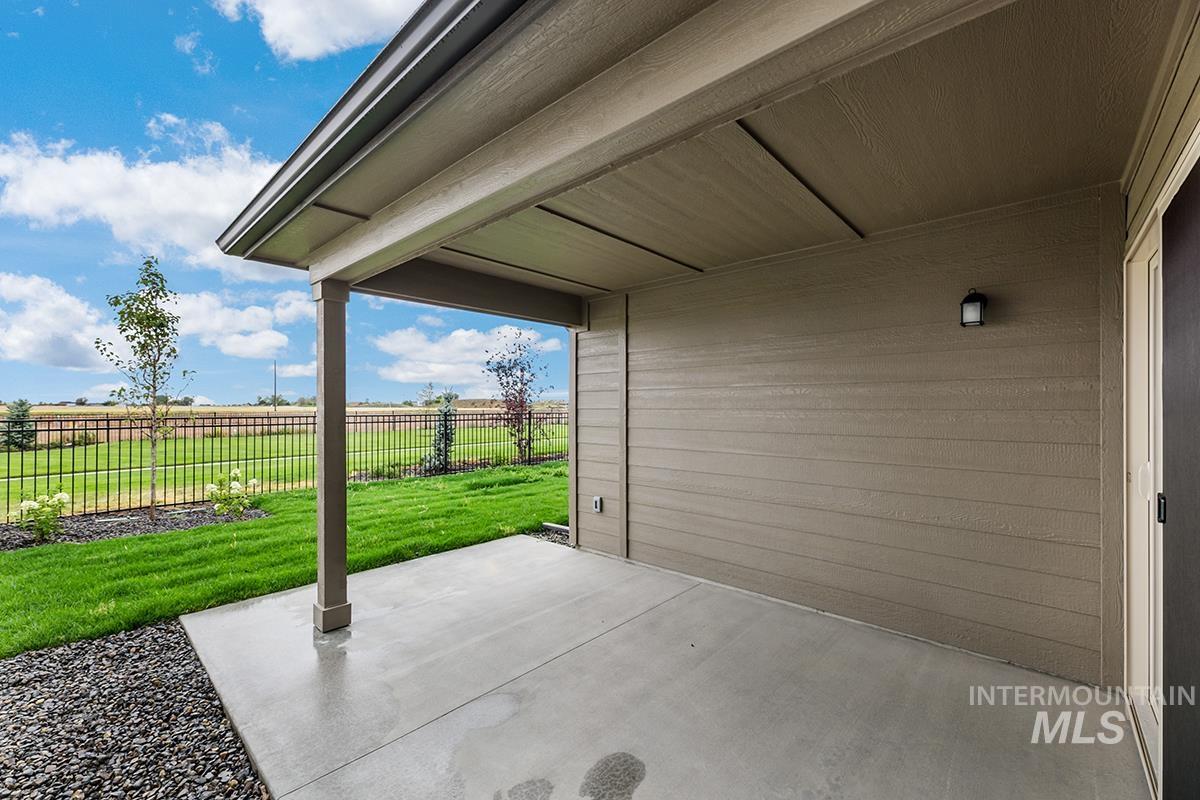 Covered concrete patio with durable siding exterior, overhead lighting fixture, and black metal fencing