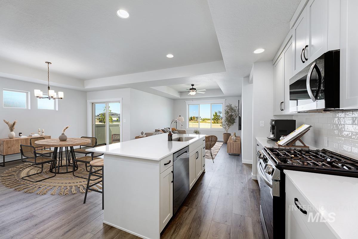 Modern kitchen featuring a large central island with seating, stainless steel appliances, and white shaker cabinetry