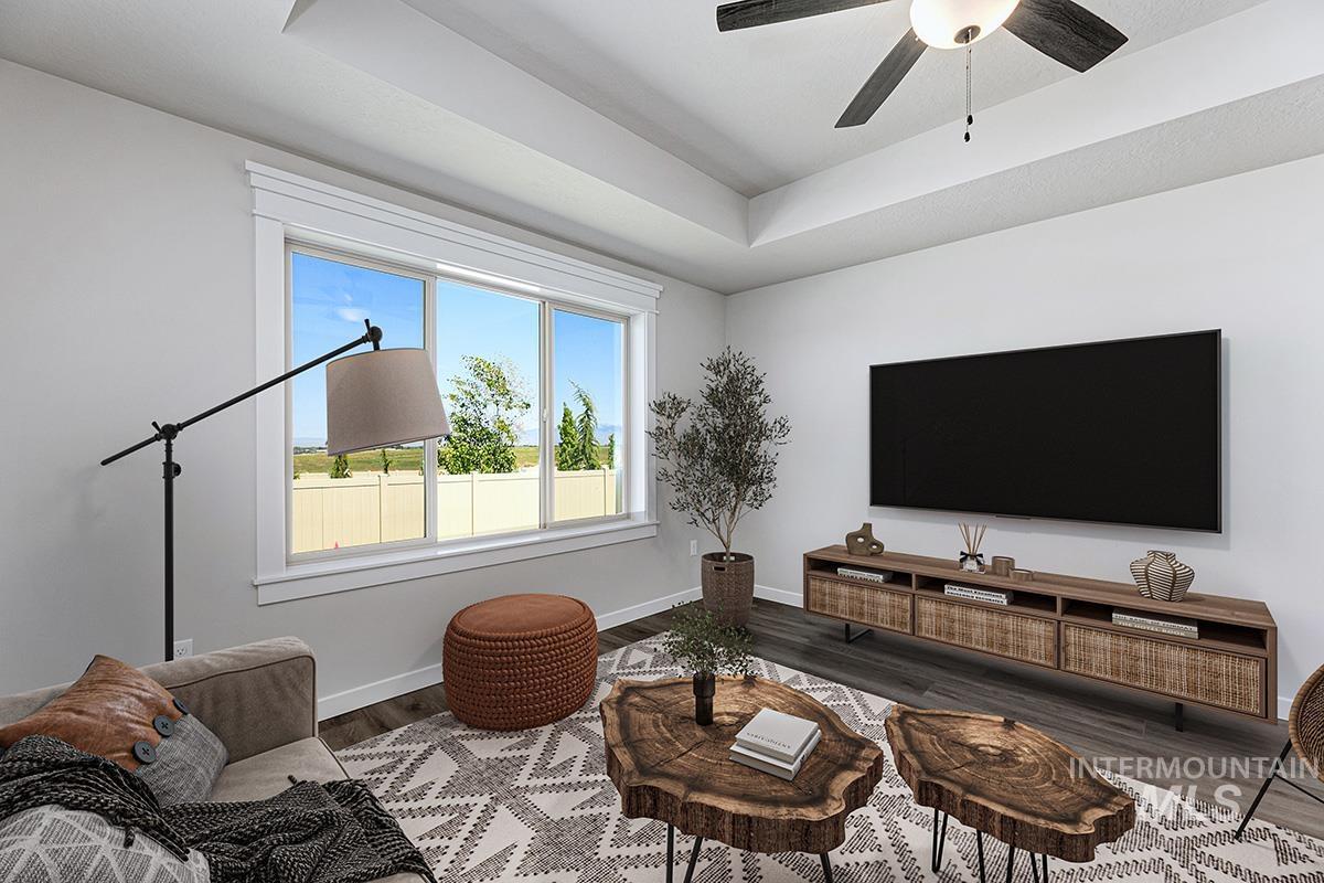 Living space featuring a tray ceiling, ceiling fan with integrated lighting, wood-finish flooring, and a large window with white trim