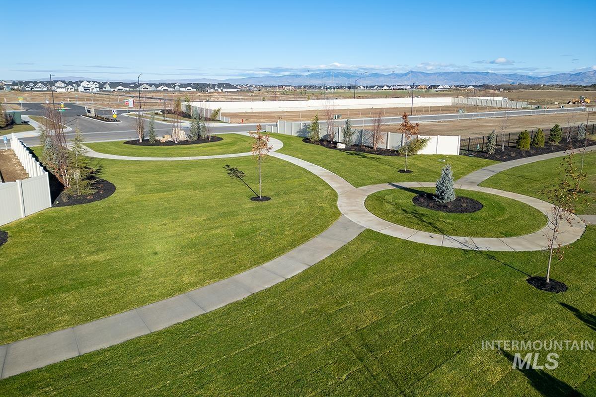 Expansive green space featuring curved concrete pathways, manicured lawns, and young trees