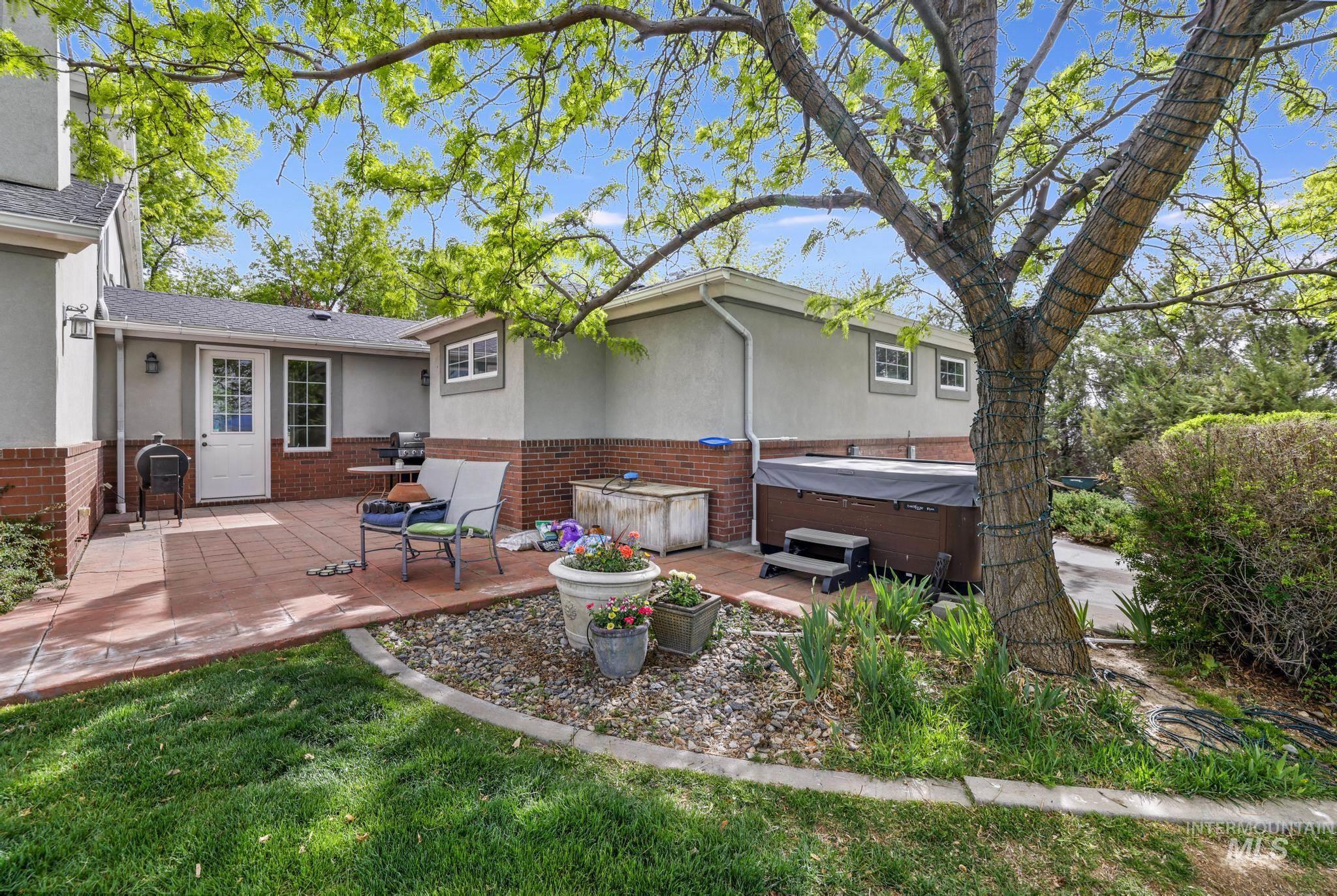 Back of property with a hot tub, brick siding, a patio, and stucco siding