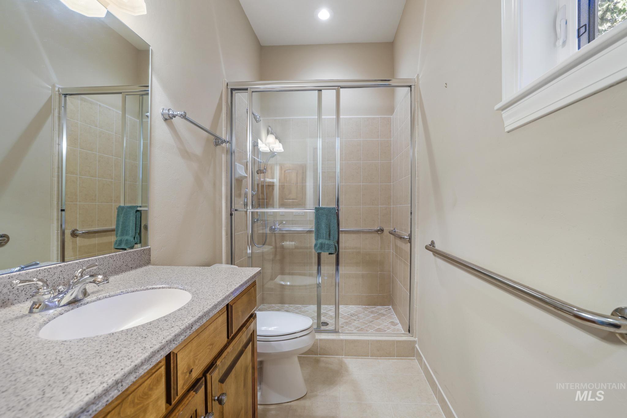 Bathroom with vanity, a stall shower, and light tile patterned floors