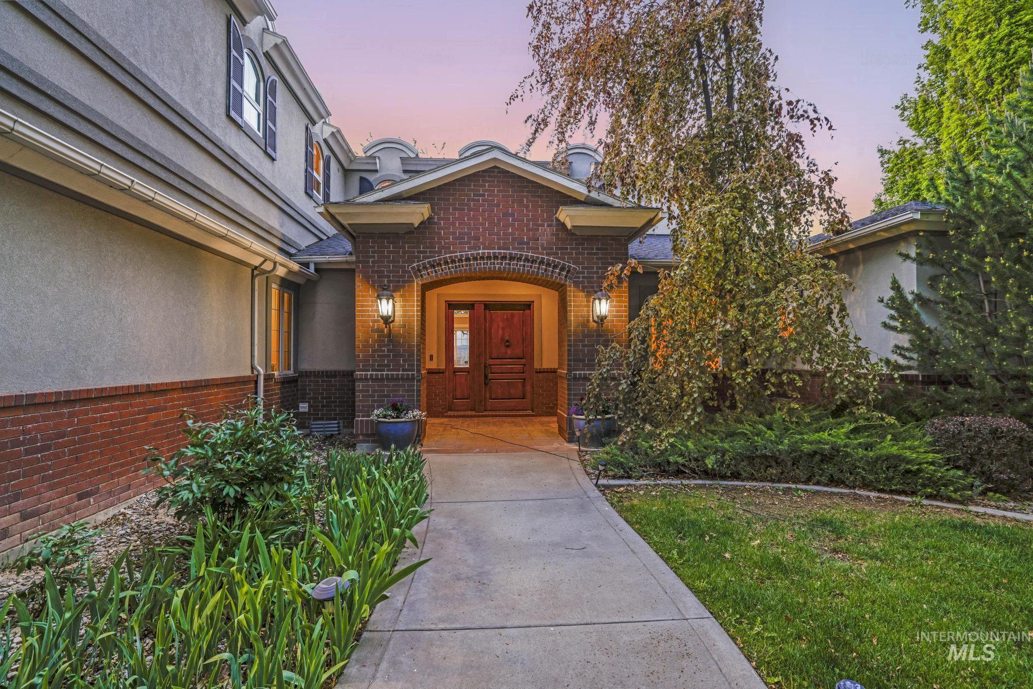 Property entrance with brick siding, stucco siding, and a lawn