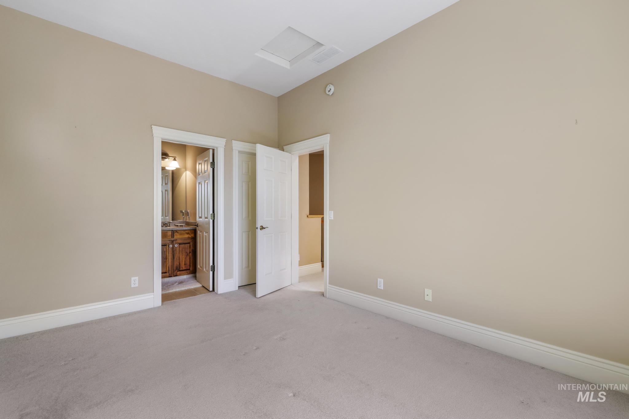 Unfurnished bedroom featuring attic access, carpet flooring, and ensuite bath