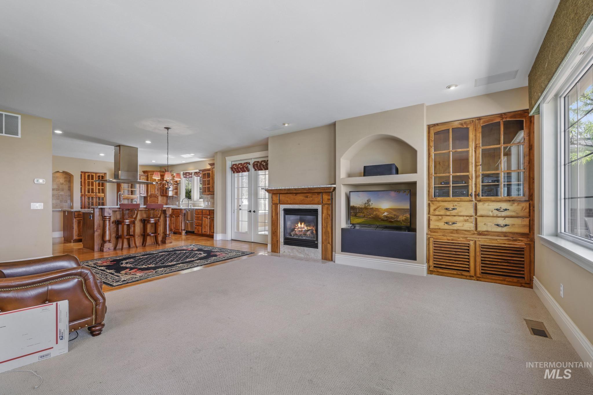 Living area with light carpet, a premium fireplace, built in shelves, a chandelier, and arched walkways