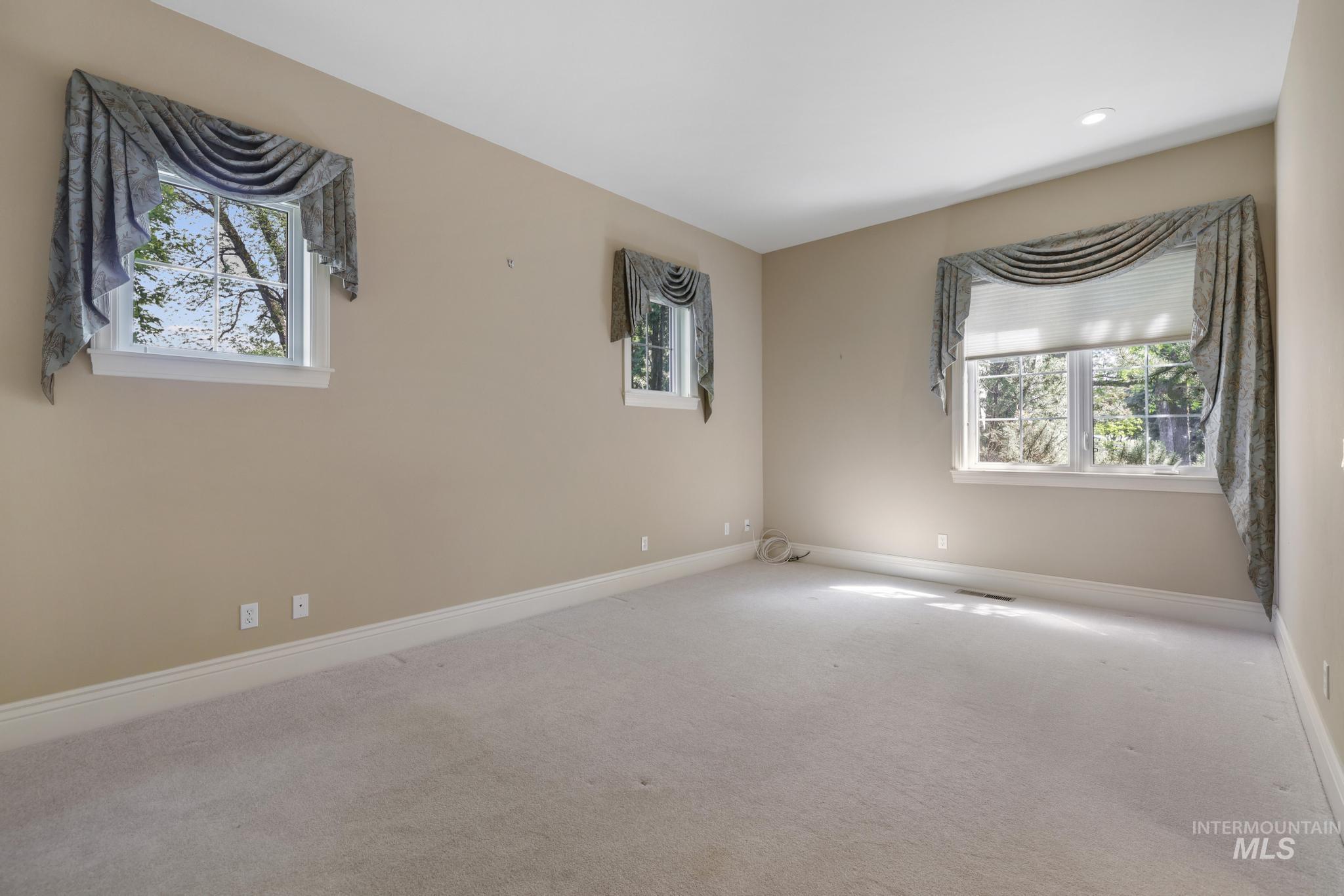 Carpeted empty room featuring healthy amount of natural light