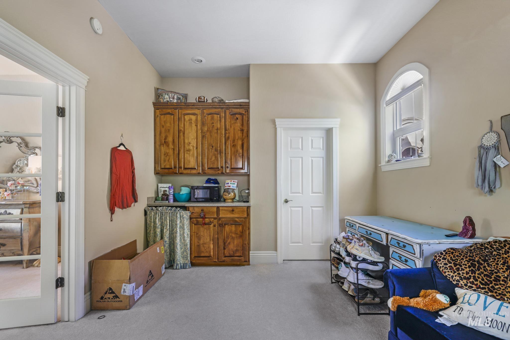 Dry Kitchen in the bedroom ensuite featuring light carpet, brown cabinetry, and light countertops