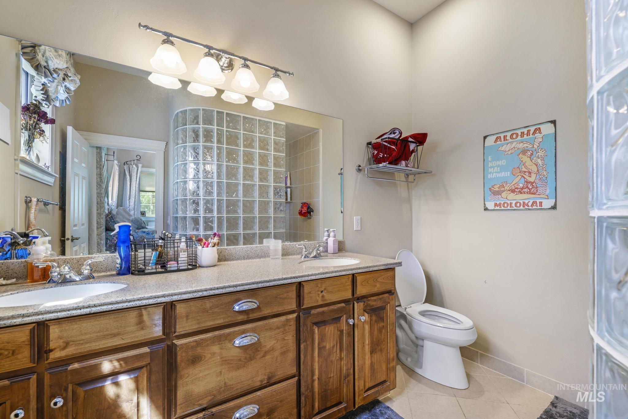Ensuite bathroom with light tile patterned floors and double vanity
