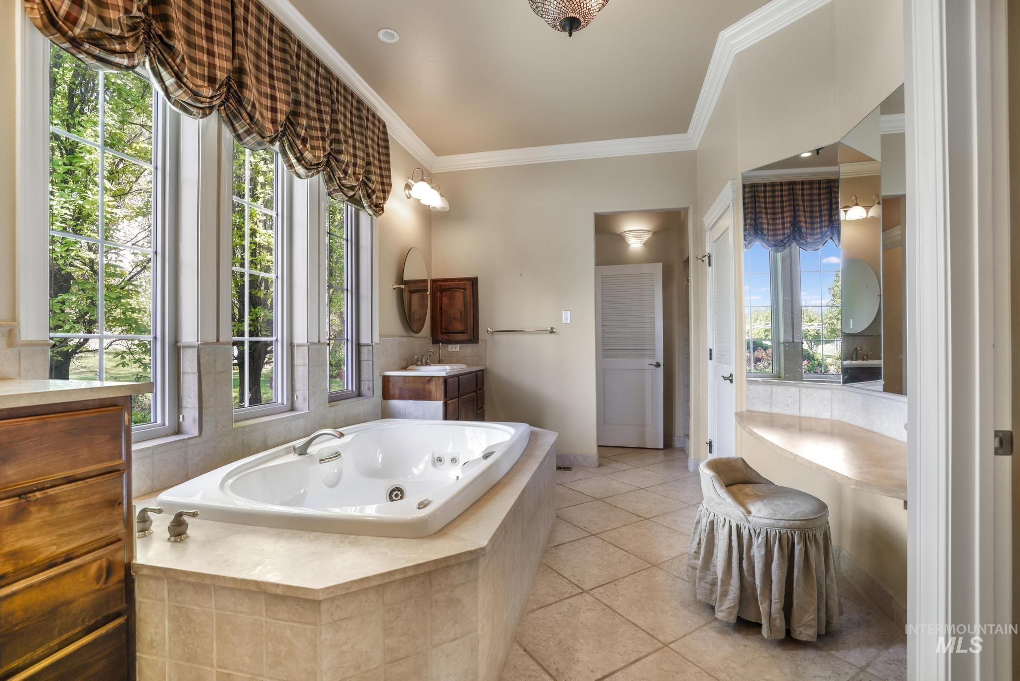 Bathroom featuring vanity, crown molding, a jetted tub, and light tile patterned floors