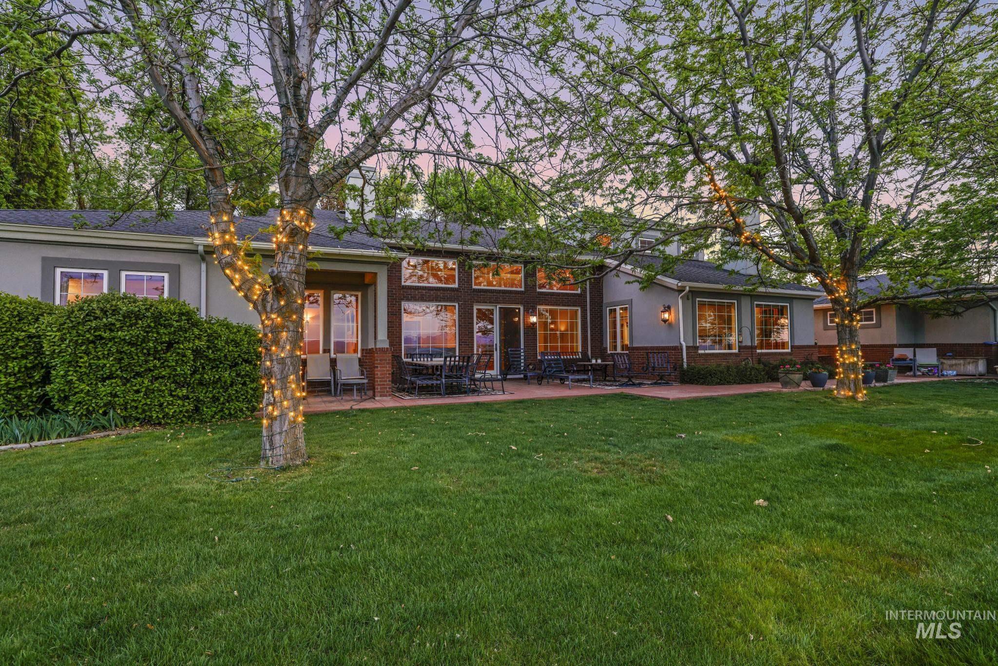 Rear view of house with brick siding, a yard, a patio, and stucco siding