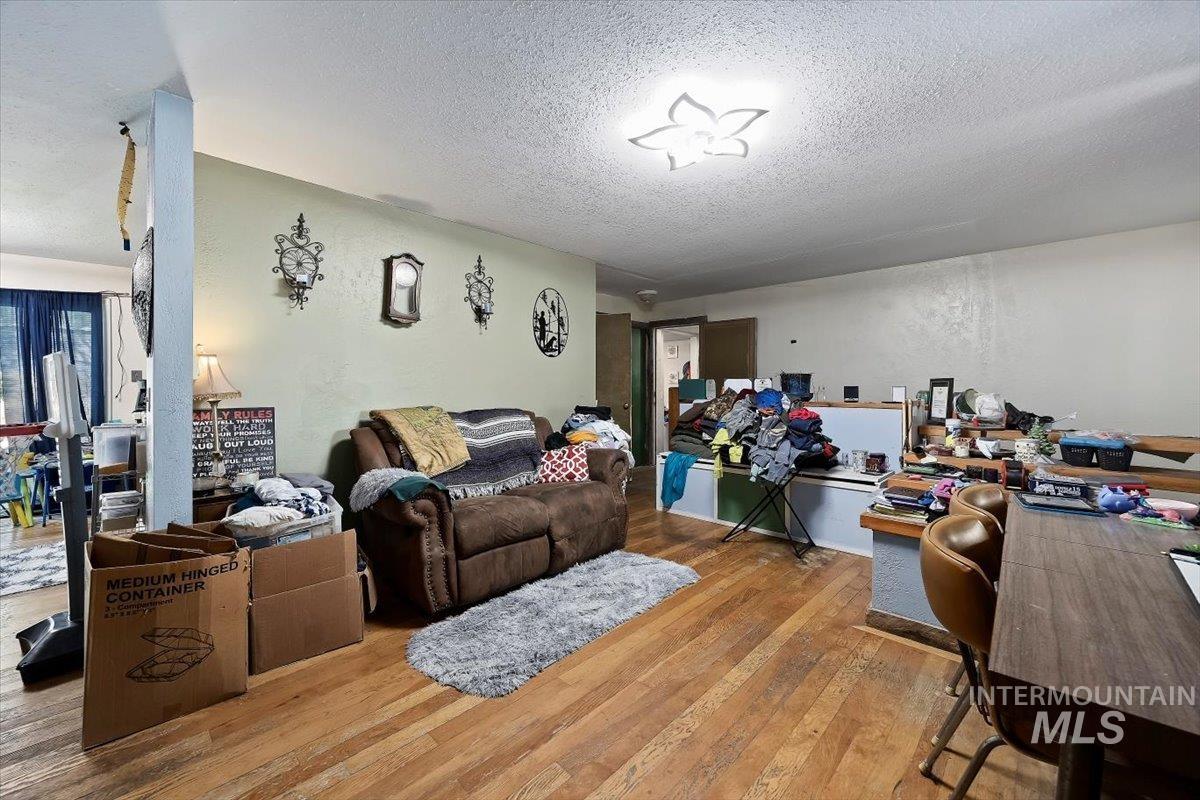 Living area with light wood-style flooring, a textured ceiling, a textured wall, and an office area