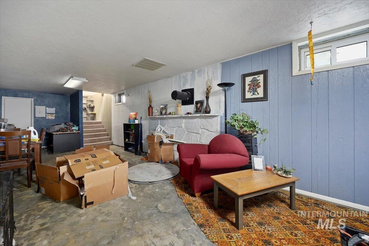 Below grade area featuring stairs, a textured ceiling, and wooden walls