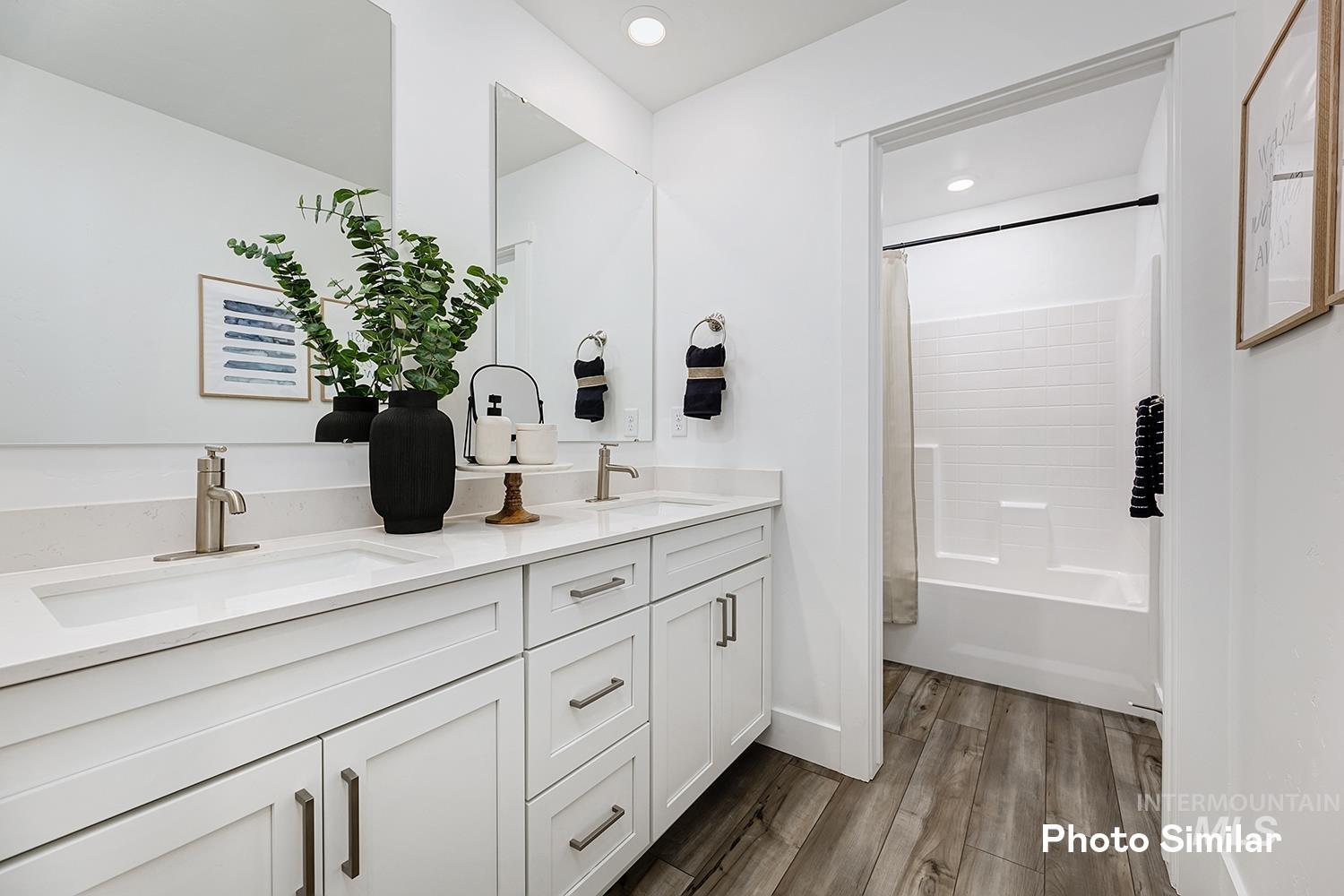 Bathroom with shower / bathtub combination with curtain, double vanity, dark wood-style flooring, and recessed lighting
