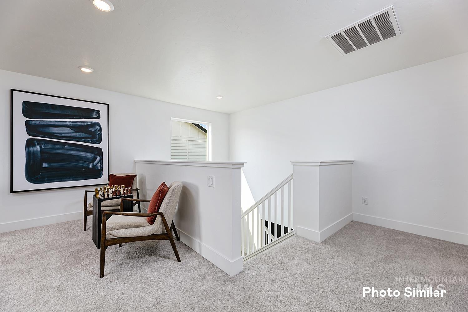 Sitting room with an upstairs landing, light colored carpet, and recessed lighting
