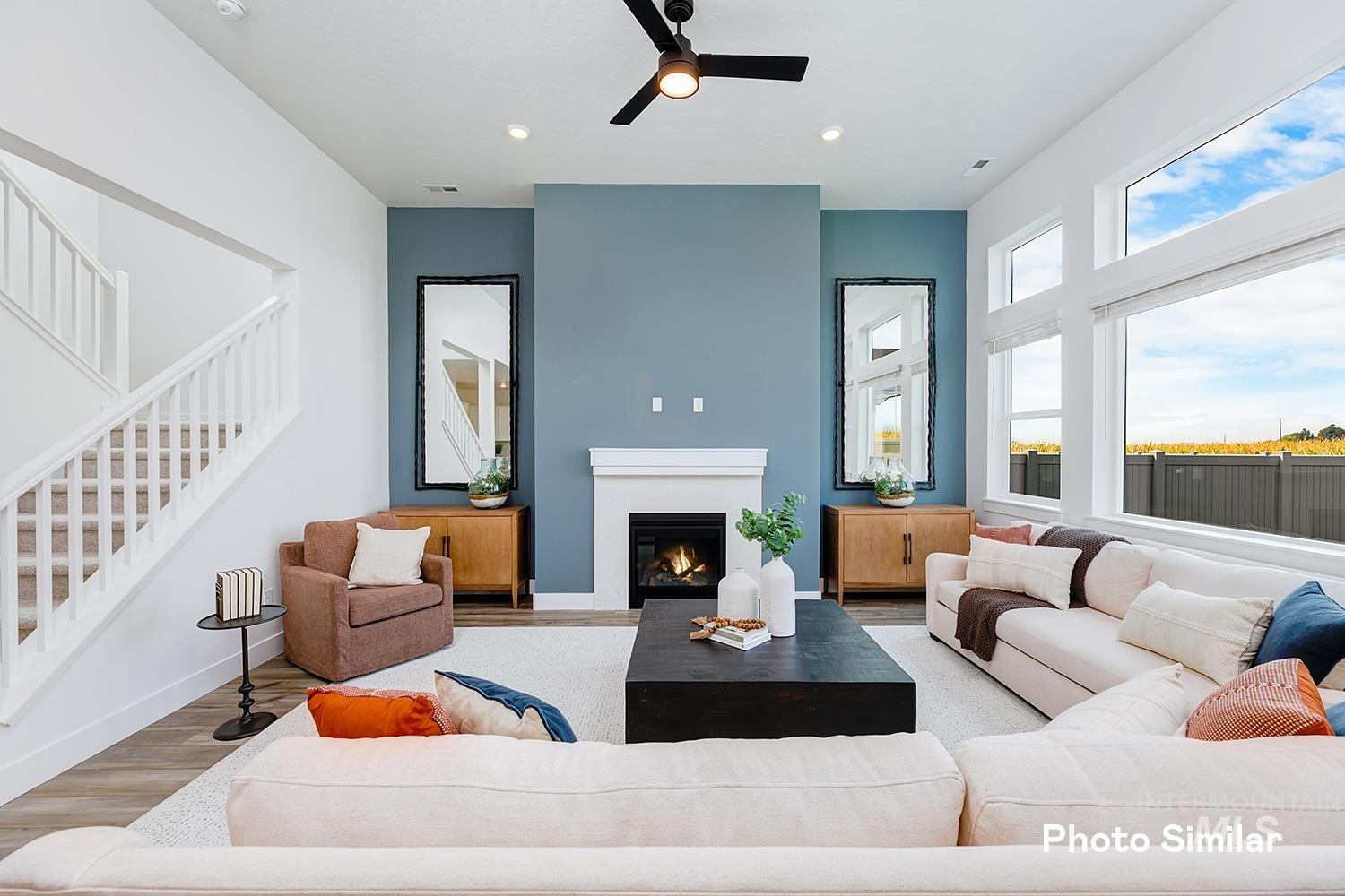 Living room with stairway, wood finished floors, a ceiling fan, a glass covered fireplace, and recessed lighting