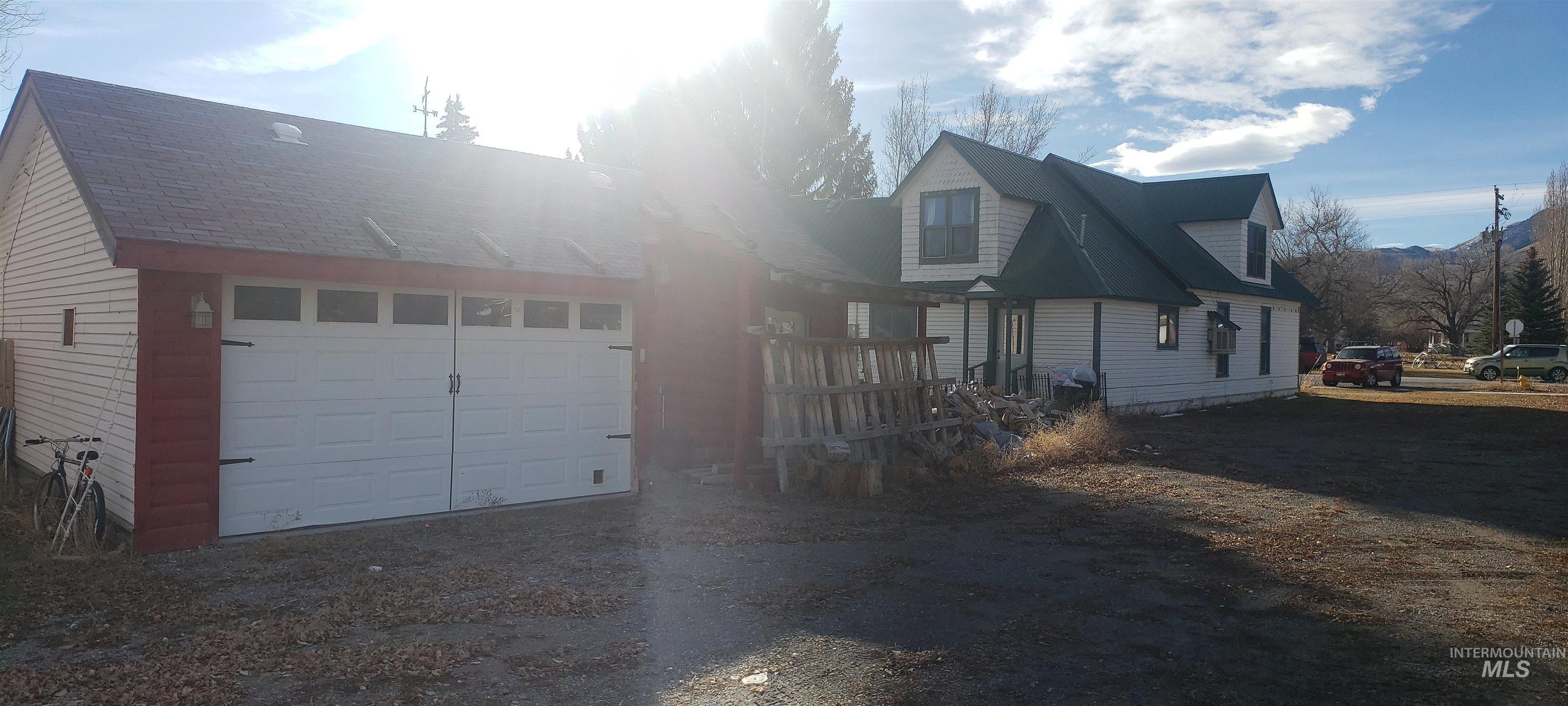 View of front of house featuring an attached garage and dirt driveway
