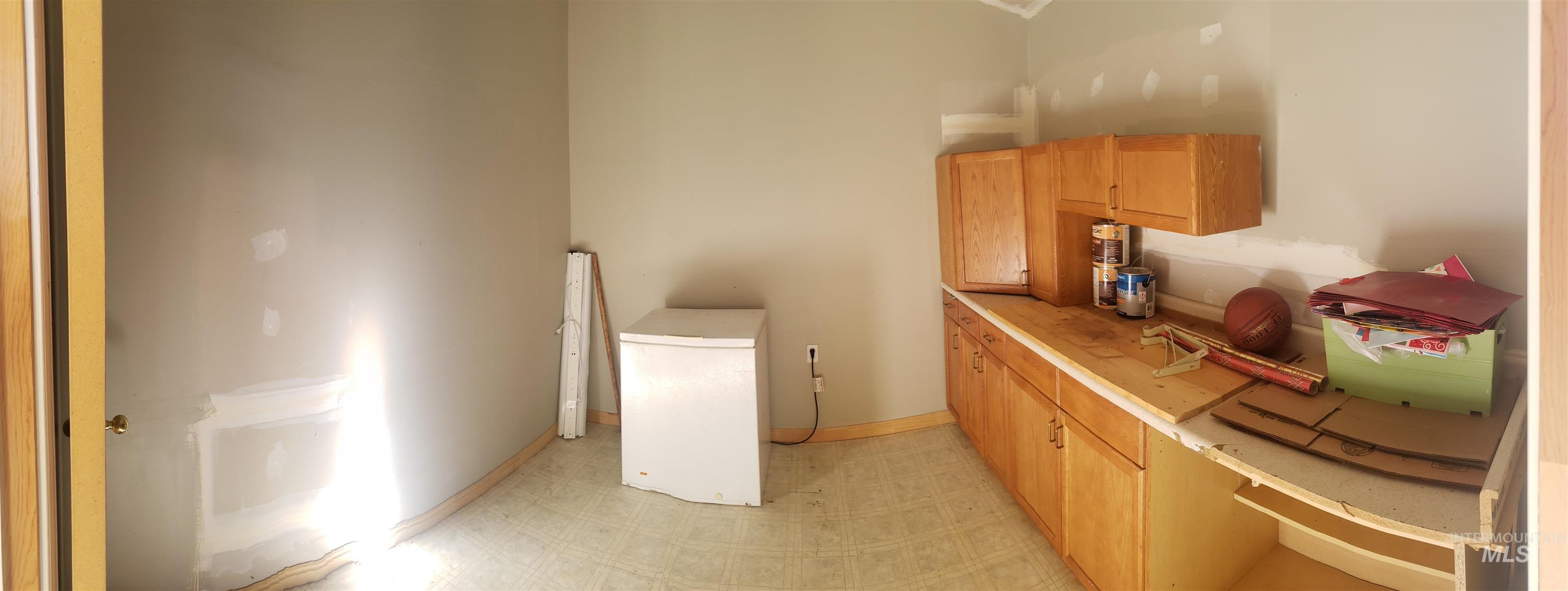 Laundry area featuring light flooring and baseboards