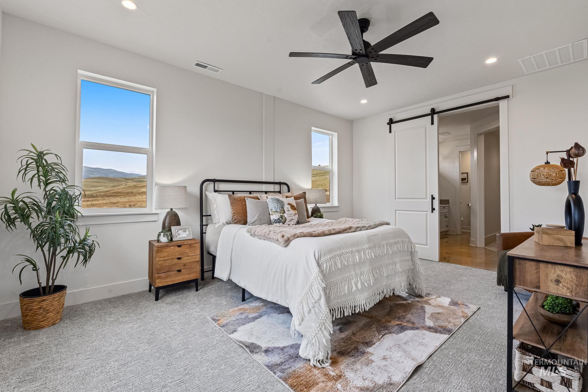 Bedroom featuring a barn door, a ceiling fan, light carpet, and recessed lighting