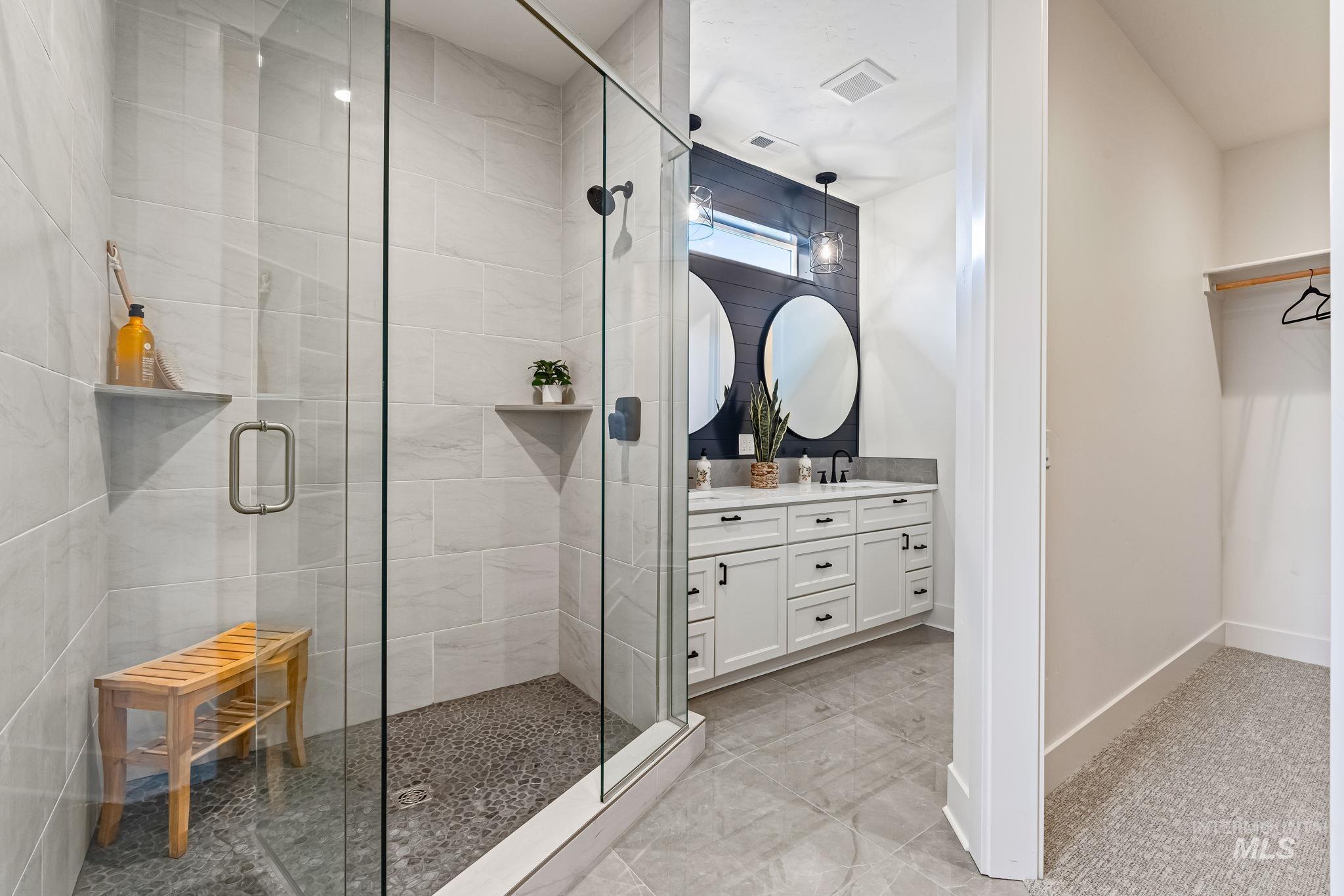 Full bath with vanity, a stall shower, and a spacious closet