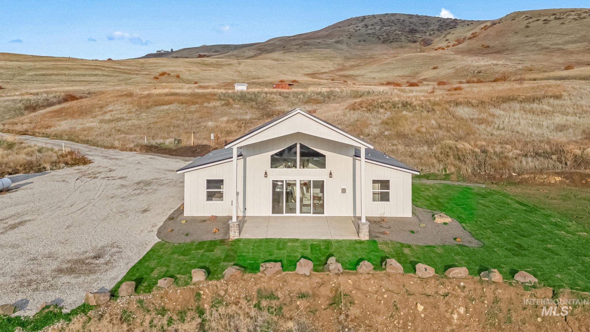 Back of property with a mountain view, a patio, and a lawn