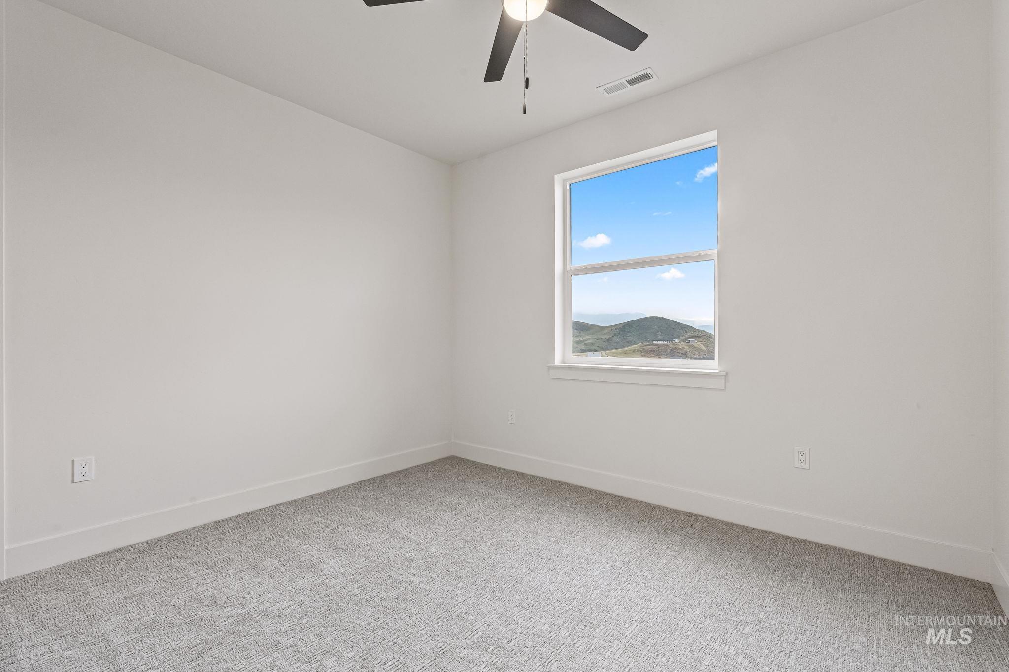 Empty room featuring light colored carpet and ceiling fan