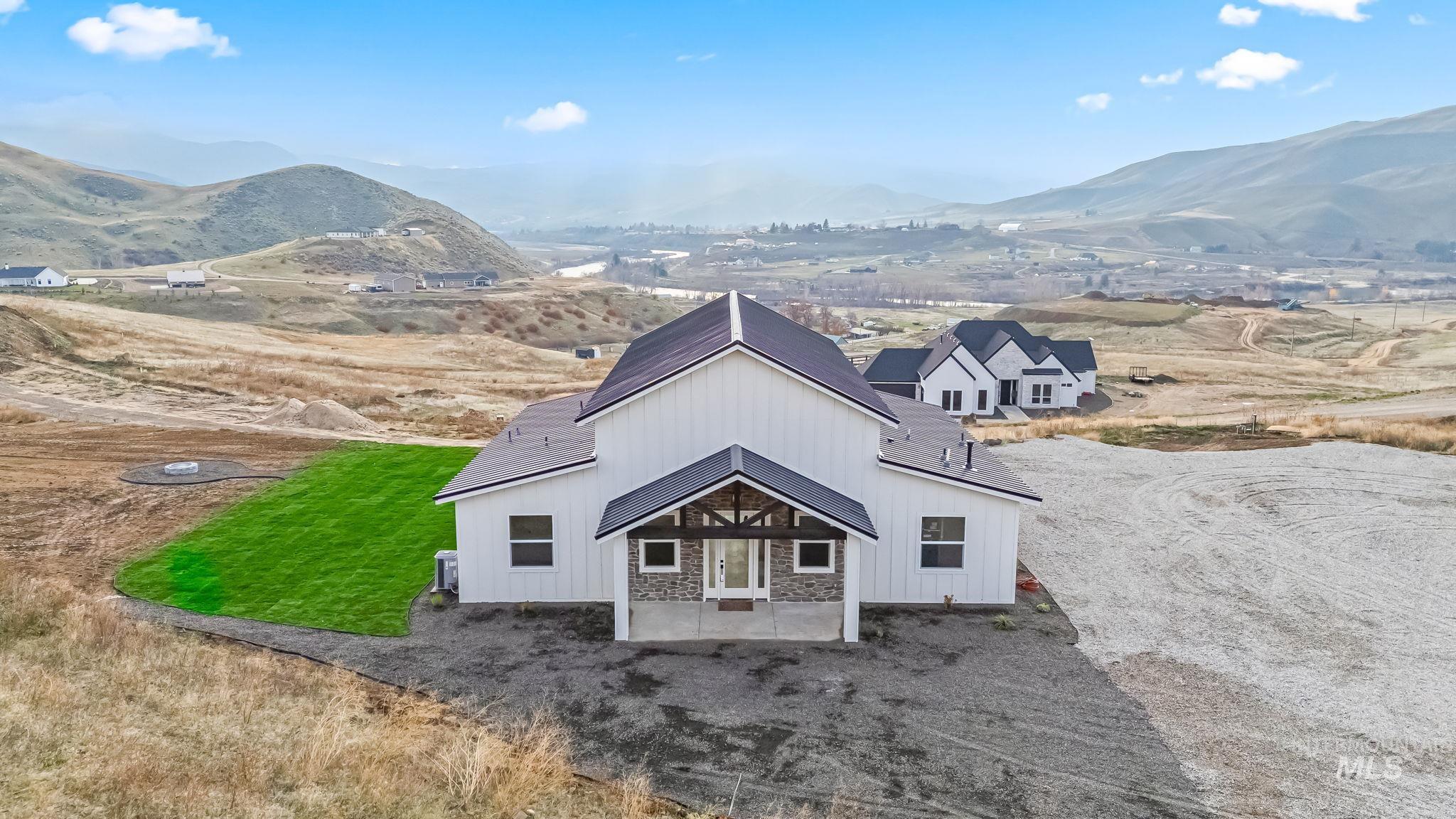 Back of house featuring a patio, stone siding, board and batten siding, and a mountain view
