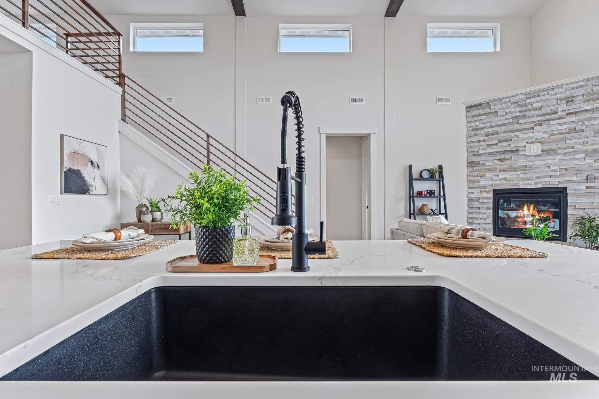 Kitchen view of light stone counters and a glass covered fireplace