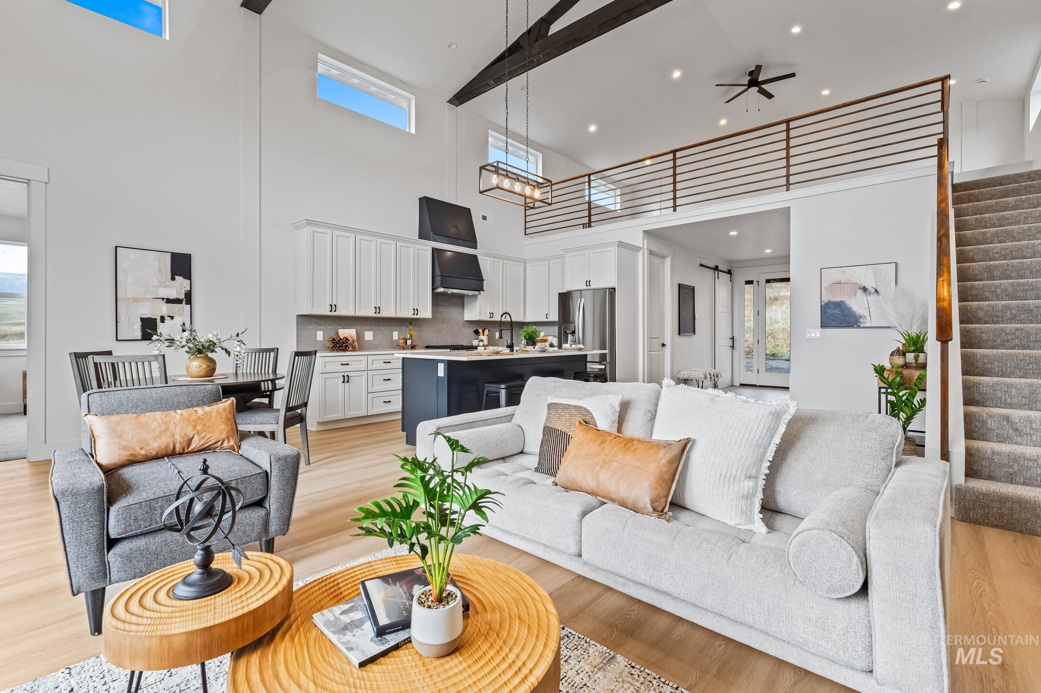 Living room featuring stairway, light wood-style floors, ceiling fan, a high ceiling, and recessed lighting