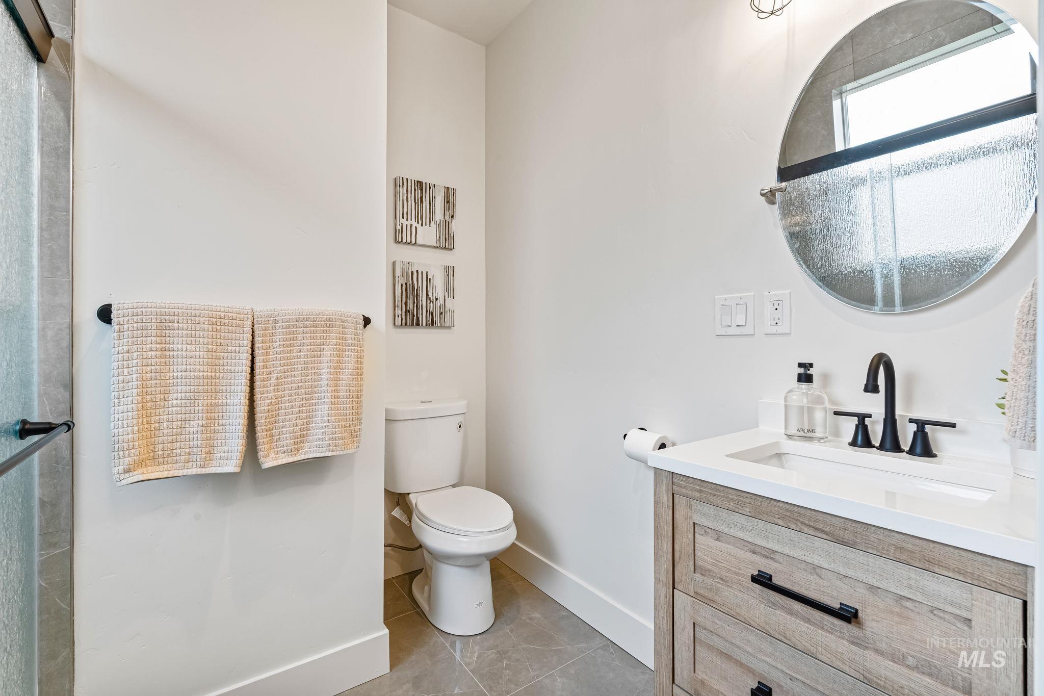 Full bath with vanity, light tile patterned floors, and a shower with door