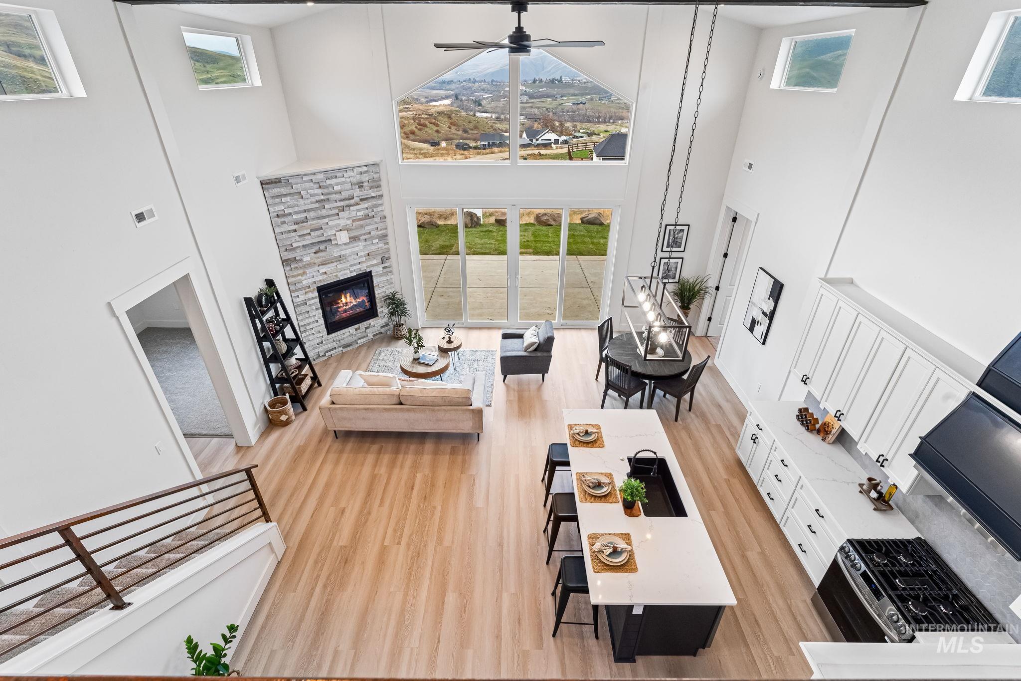 Living area featuring a towering ceiling, a fireplace, ceiling fan, and light wood finished floors