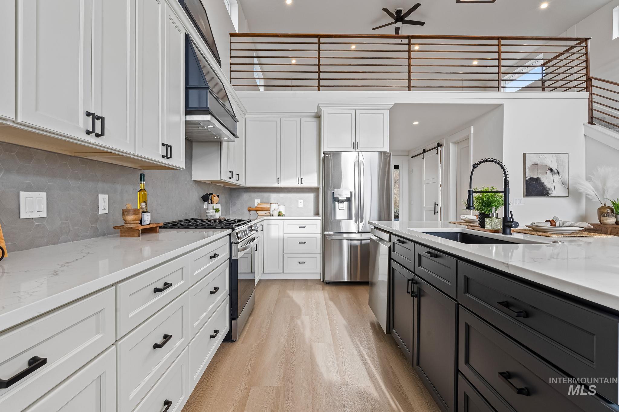 Kitchen with light stone counters, white cabinets, stainless steel appliances, decorative backsplash, and recessed lighting