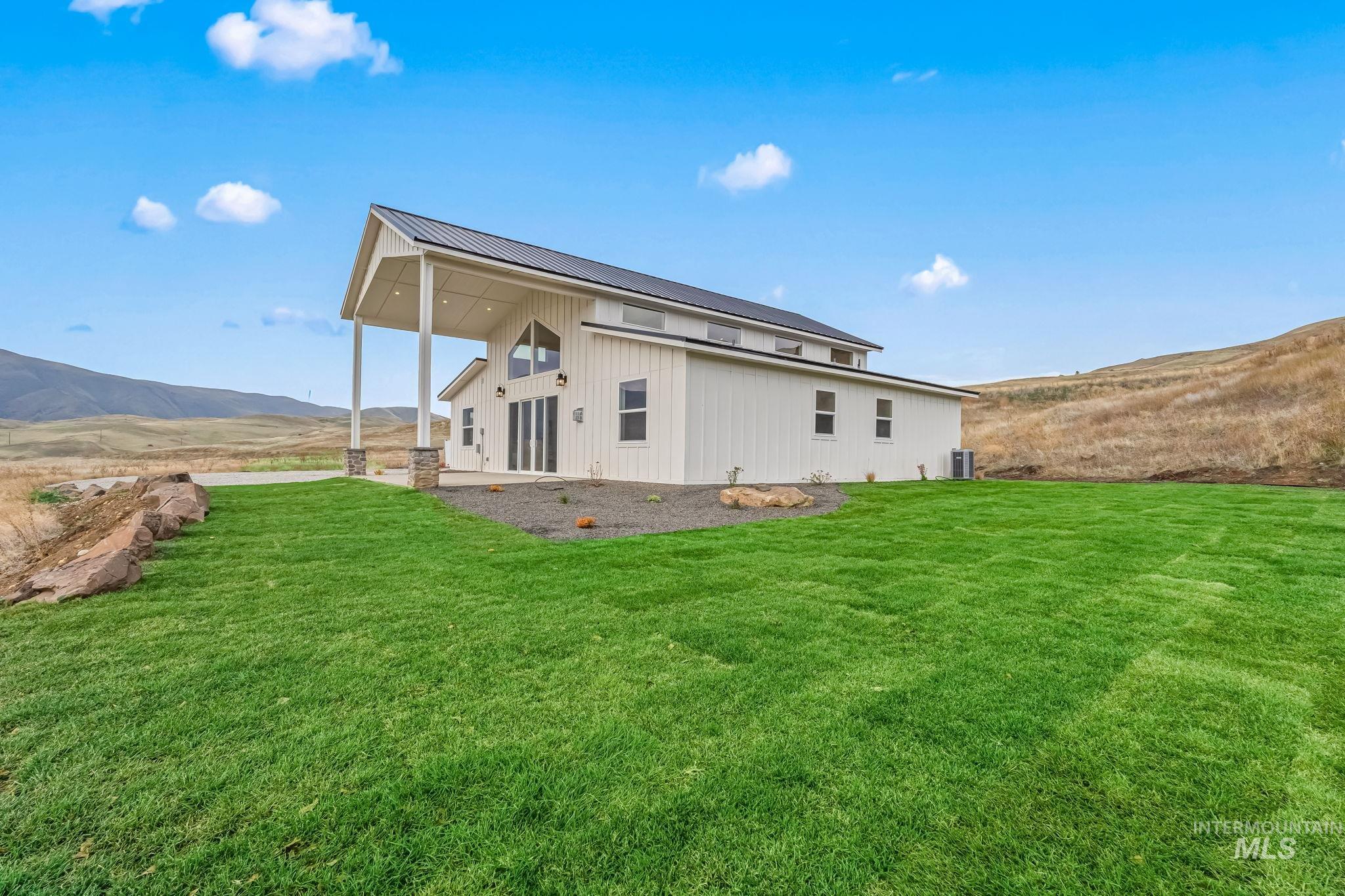 Rear view of house featuring a mountain view, a yard, a metal roof, and a patio area