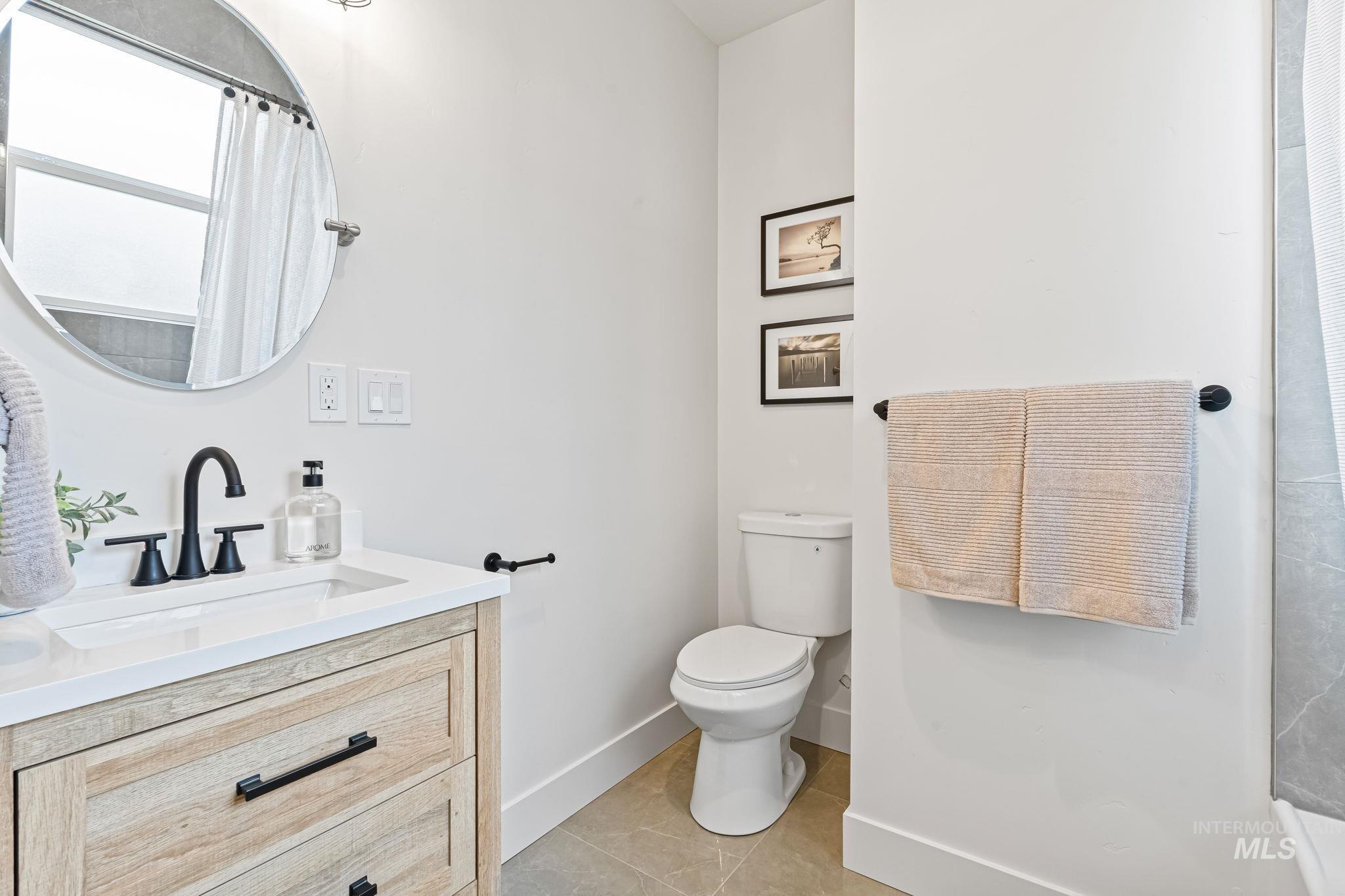 Full bathroom featuring curtained shower, vanity, and light tile patterned floors