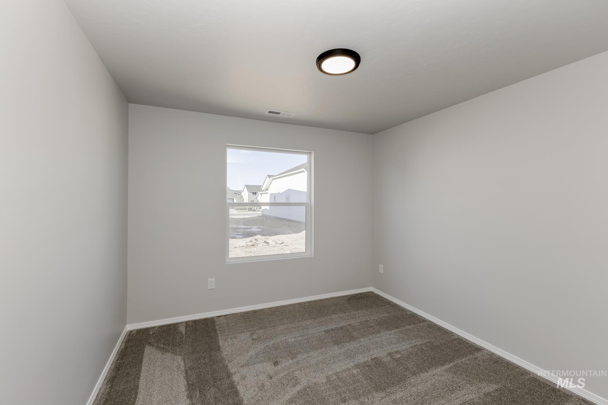 Empty room with dark colored carpet and baseboards