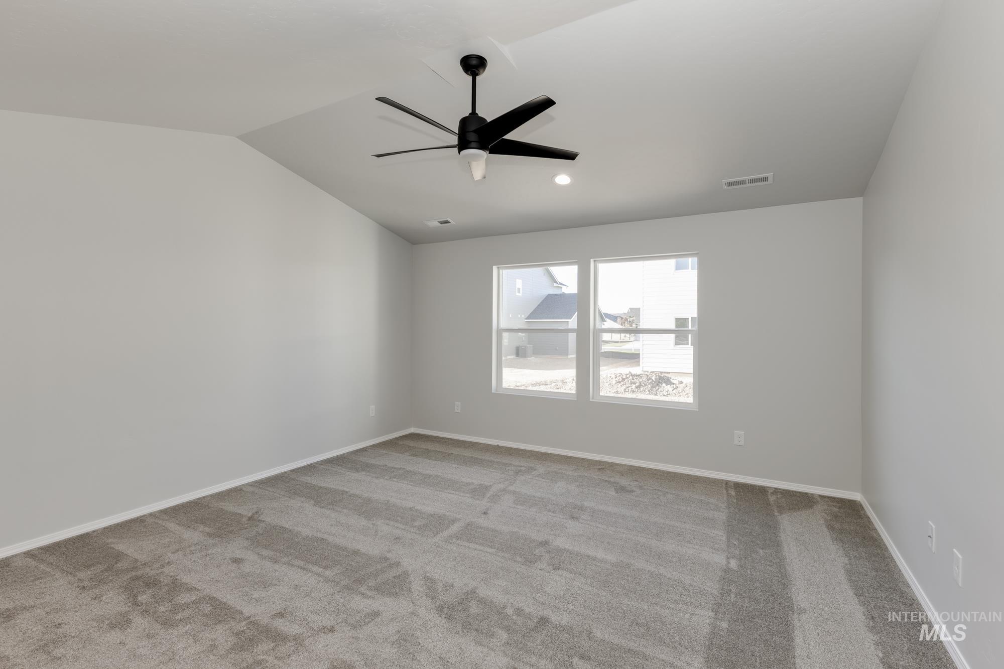 Carpeted empty room featuring lofted ceiling, a ceiling fan, and recessed lighting