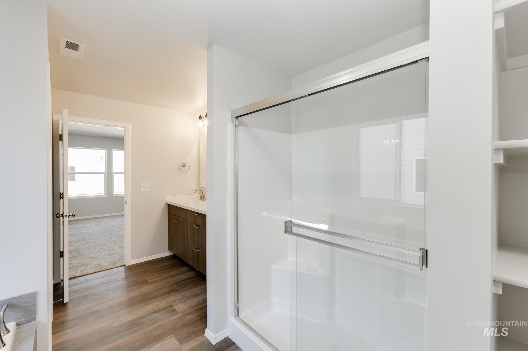 Full bathroom featuring vanity, a stall shower, and wood finished floors
