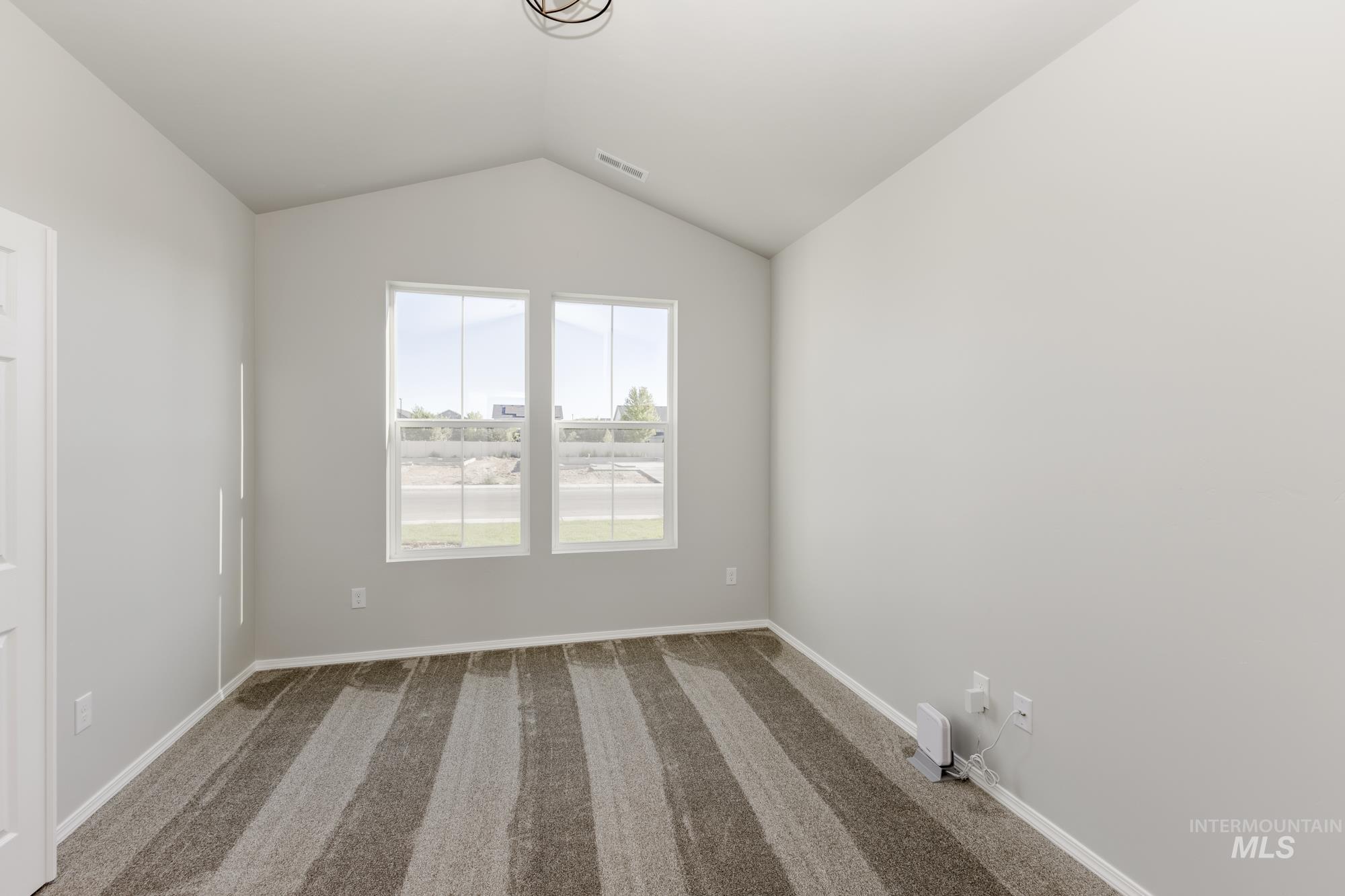 Spare room featuring vaulted ceiling and carpet flooring