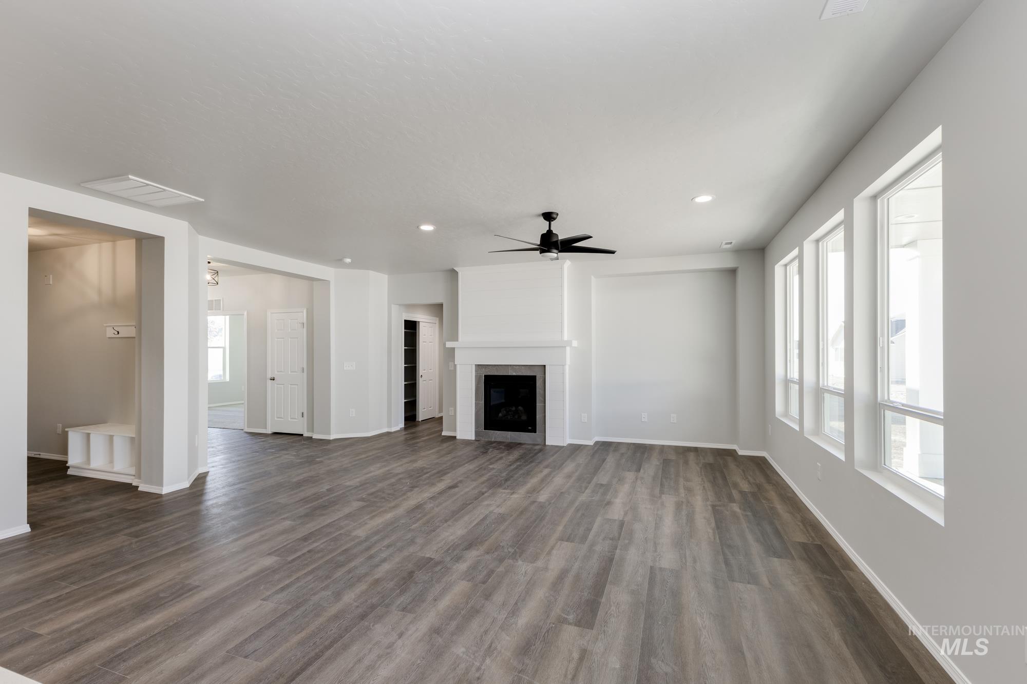 Unfurnished living room featuring ceiling fan, dark wood-type flooring, recessed lighting, and a fireplace