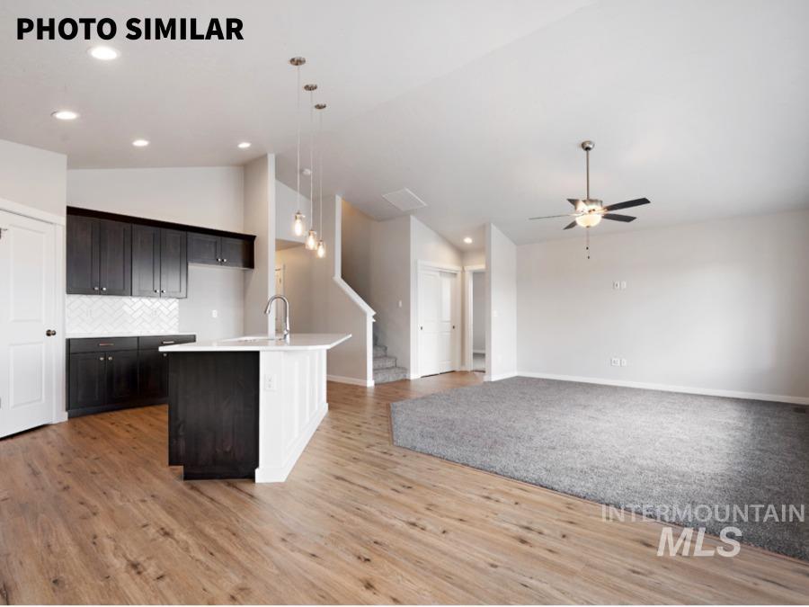 Open-concept main living area with wood-finish flooring extending into the kitchen
